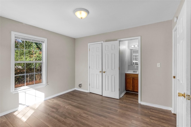 unfurnished bedroom with dark hardwood / wood-style flooring, sink, a closet, and ensuite bathroom