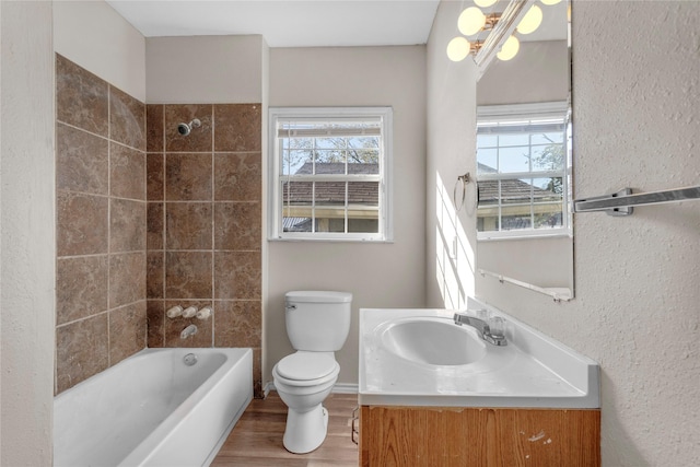 full bathroom with hardwood / wood-style flooring, vanity, toilet, and tiled shower / bath combo