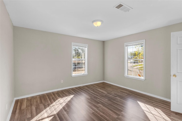 empty room featuring plenty of natural light and dark hardwood / wood-style flooring