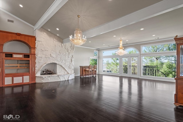 unfurnished living room with hardwood / wood-style flooring, crown molding, a stone fireplace, and a notable chandelier