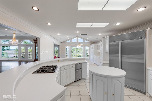 kitchen featuring lofted ceiling, white cabinetry, a center island, appliances with stainless steel finishes, and ornamental molding