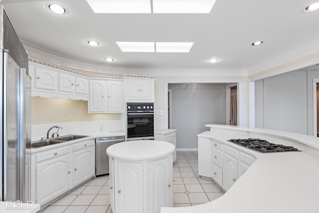 kitchen featuring sink, white cabinetry, a skylight, ornamental molding, and appliances with stainless steel finishes