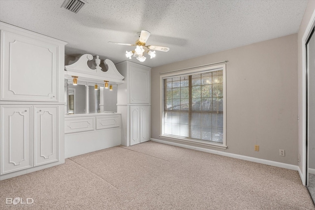 unfurnished dining area featuring ceiling fan, light carpet, and a textured ceiling