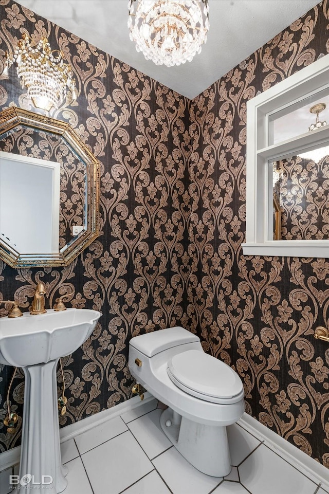 bathroom featuring toilet, tile patterned flooring, and a notable chandelier