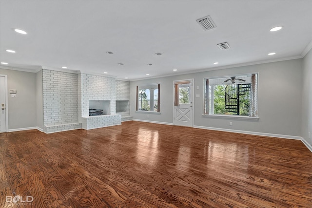 unfurnished living room with brick wall, ornamental molding, hardwood / wood-style floors, and a brick fireplace