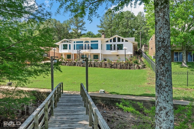 back of property featuring a balcony and a lawn