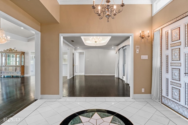 entrance foyer with an inviting chandelier, ornamental molding, and light tile patterned flooring