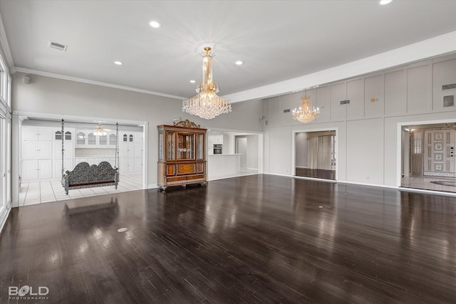 unfurnished living room with an inviting chandelier, hardwood / wood-style flooring, and ornamental molding