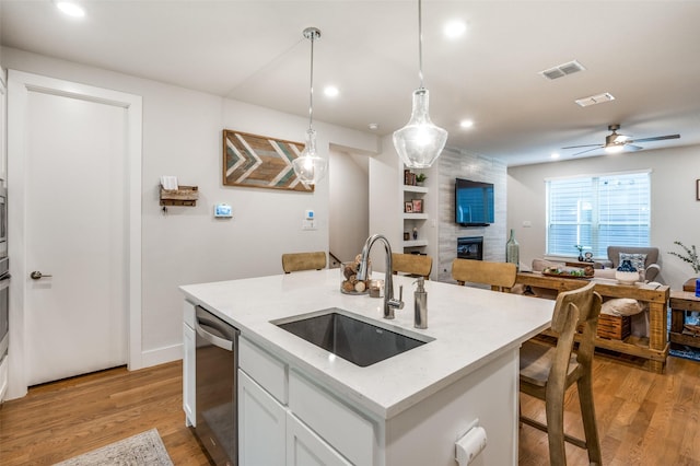 kitchen with sink, white cabinetry, dishwasher, pendant lighting, and a kitchen island with sink