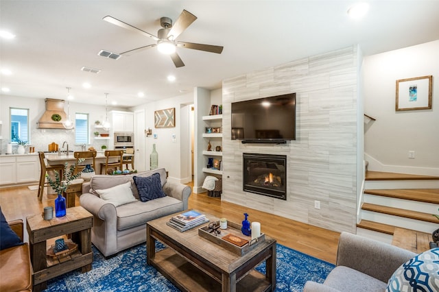 living room featuring ceiling fan, dark hardwood / wood-style floors, sink, and a fireplace