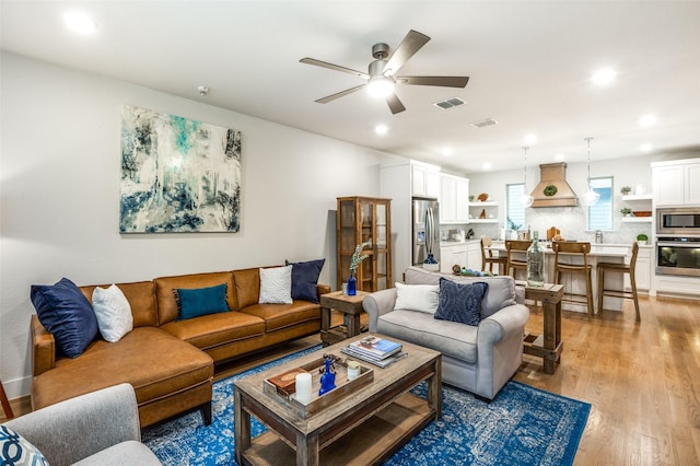 living room featuring ceiling fan and light hardwood / wood-style flooring