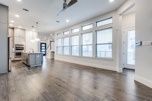 living room featuring dark hardwood / wood-style flooring, a wealth of natural light, and ceiling fan