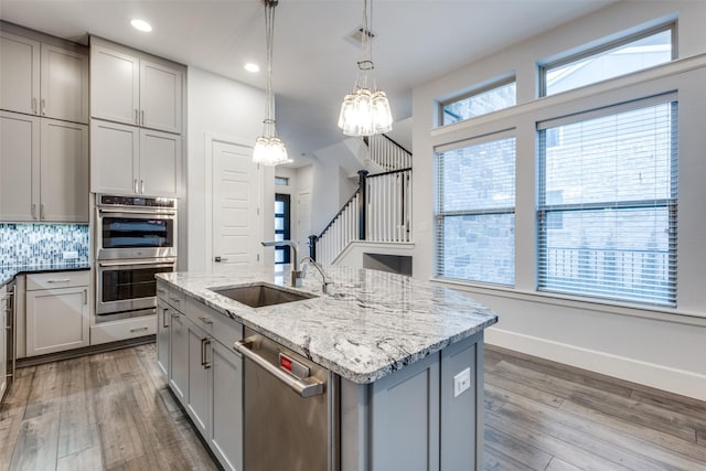 kitchen with gray cabinets, an island with sink, appliances with stainless steel finishes, and sink