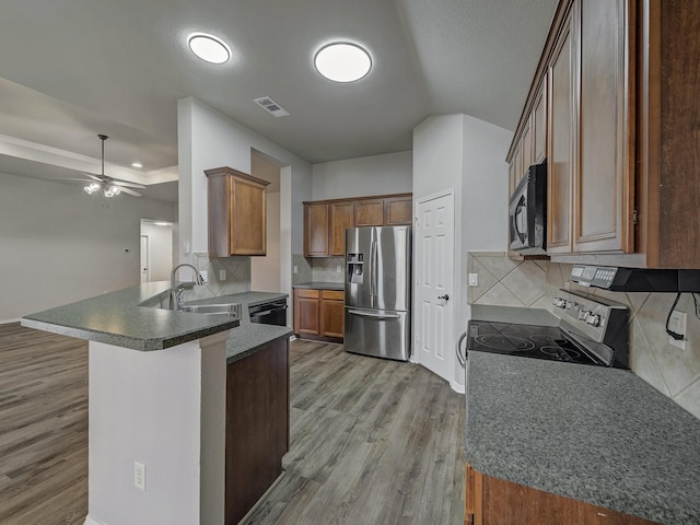 kitchen with black appliances, sink, ceiling fan, kitchen peninsula, and light wood-type flooring