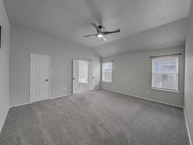 unfurnished bedroom with lofted ceiling, connected bathroom, ceiling fan, and carpet