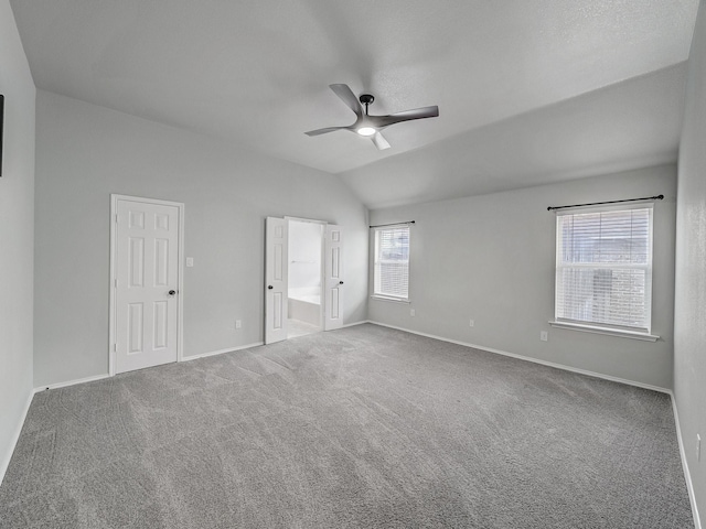 unfurnished bedroom with carpet, connected bathroom, lofted ceiling, and ceiling fan