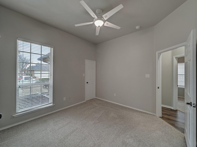 carpeted spare room featuring ceiling fan