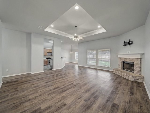 821 Grace Ln, Saginaw, TX 76179 - unfurnished living room with a raised ceiling, a brick fireplace, baseboards, dark wood finished floors, and a ceiling fan