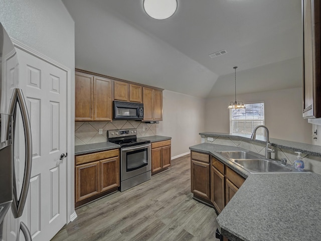 kitchen featuring sink, backsplash, hanging light fixtures, stainless steel appliances, and vaulted ceiling