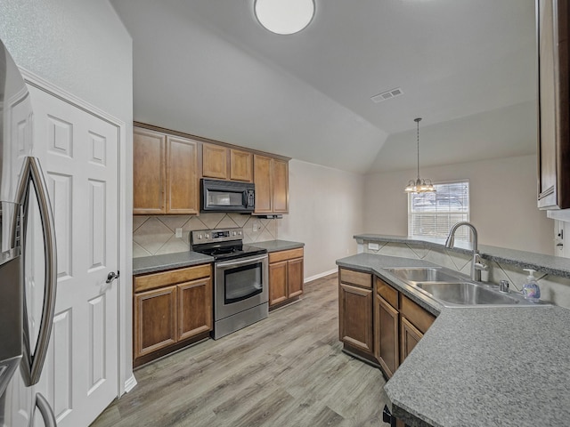 kitchen with vaulted ceiling, appliances with stainless steel finishes, decorative light fixtures, tasteful backsplash, and sink