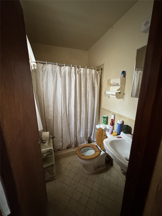 bathroom featuring sink, tile walls, curtained shower, tile patterned floors, and toilet