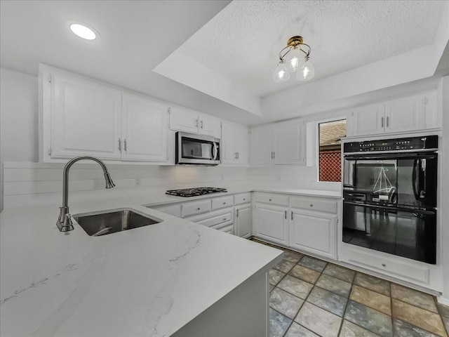 kitchen featuring sink, appliances with stainless steel finishes, white cabinetry, backsplash, and kitchen peninsula