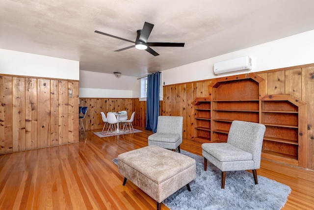 unfurnished room featuring ceiling fan, wooden walls, hardwood / wood-style floors, and a wall unit AC