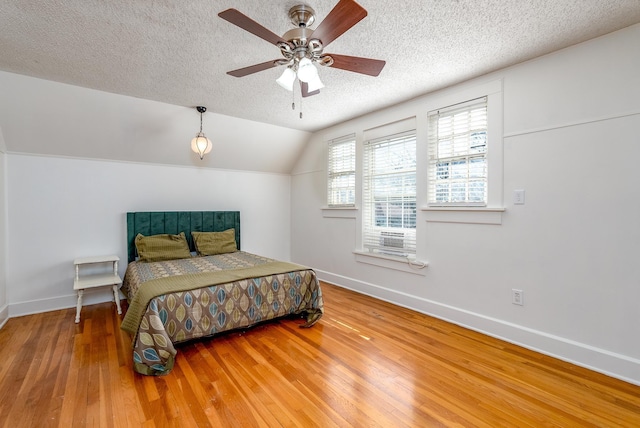 bedroom featuring hardwood / wood-style floors, vaulted ceiling, a textured ceiling, and ceiling fan