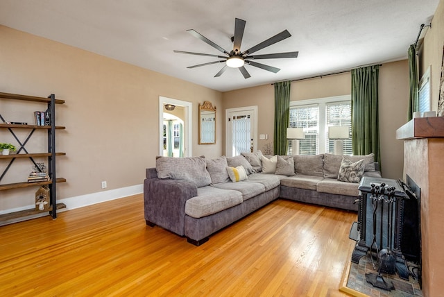 living room featuring hardwood / wood-style flooring, ceiling fan, and a fireplace