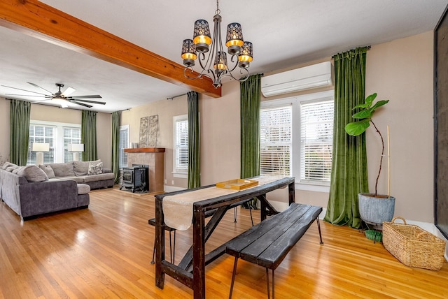 dining space with beam ceiling, light hardwood / wood-style flooring, an AC wall unit, and a healthy amount of sunlight