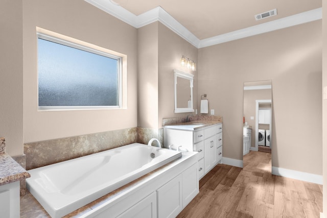 bathroom featuring vanity, hardwood / wood-style floors, washing machine and clothes dryer, and a tub to relax in