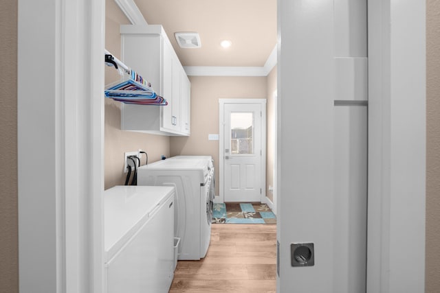 laundry room featuring independent washer and dryer, crown molding, light hardwood / wood-style floors, and cabinets