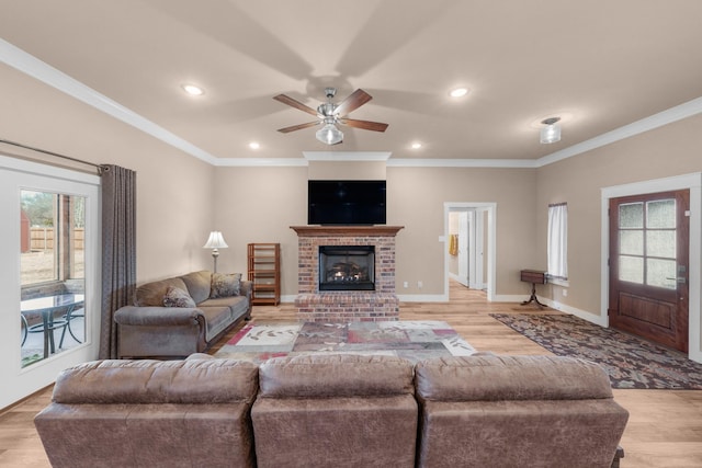 living room featuring ornamental molding, a brick fireplace, ceiling fan, and light hardwood / wood-style flooring