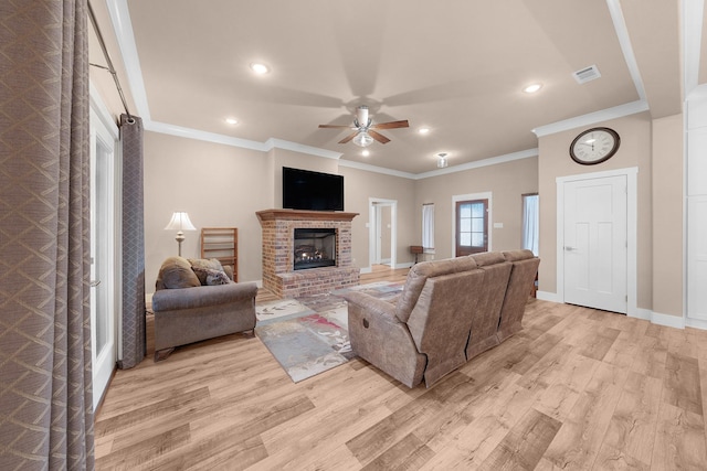 living room featuring ornamental molding, a fireplace, light hardwood / wood-style floors, and ceiling fan