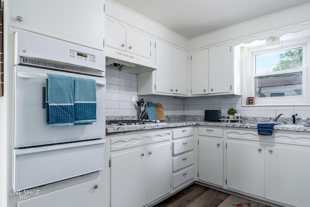 kitchen with stainless steel gas stovetop, white cabinets, backsplash, and double oven