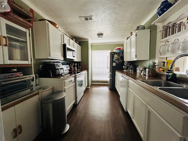 kitchen featuring sink, white appliances, dark wood-type flooring, a textured ceiling, and white cabinets