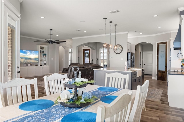 dining space with visible vents, arched walkways, dark wood finished floors, ornamental molding, and recessed lighting