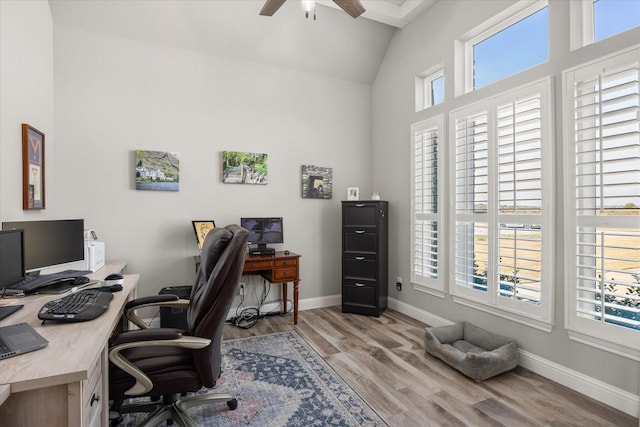 office featuring a ceiling fan, vaulted ceiling, light wood-style flooring, and baseboards