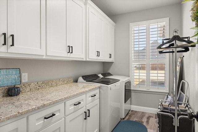 clothes washing area with a wealth of natural light, cabinet space, light wood-style flooring, and washing machine and clothes dryer