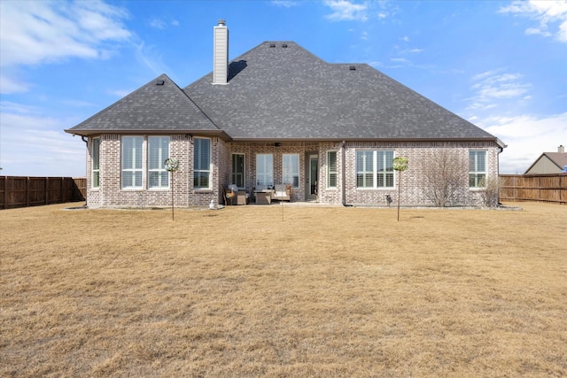 back of property with a fenced backyard, a chimney, and brick siding