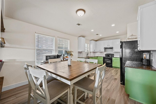 dining area featuring vaulted ceiling, sink, and light hardwood / wood-style floors