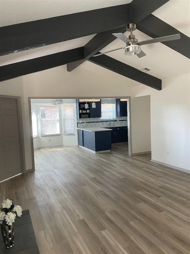 unfurnished living room with sink, dark wood-type flooring, lofted ceiling with beams, and ceiling fan