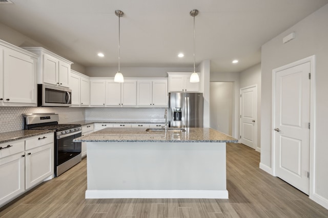 kitchen with sink, white cabinetry, decorative light fixtures, a center island with sink, and appliances with stainless steel finishes