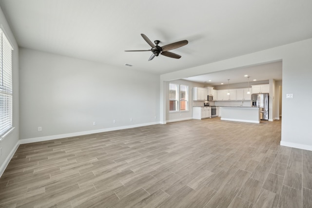 unfurnished living room with ceiling fan and light hardwood / wood-style flooring