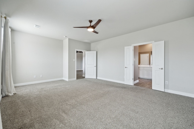 unfurnished bedroom with dark colored carpet, ceiling fan, and ensuite bath