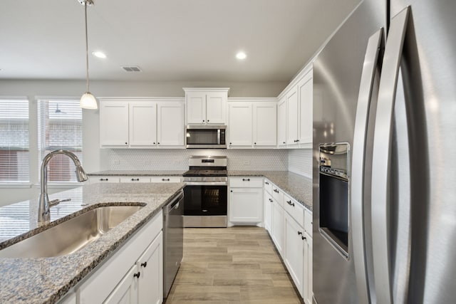 kitchen with white cabinetry, stainless steel appliances, sink, and pendant lighting