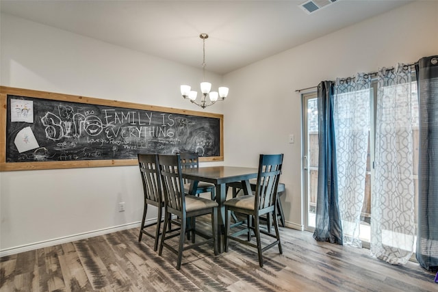 dining area with hardwood / wood-style flooring and an inviting chandelier
