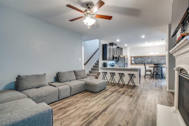 living room featuring hardwood / wood-style flooring and ceiling fan with notable chandelier