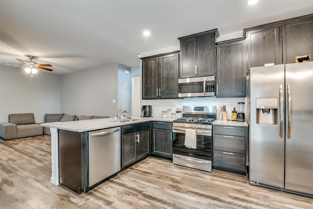 kitchen featuring decorative backsplash, kitchen peninsula, stainless steel appliances, dark brown cabinets, and light hardwood / wood-style flooring