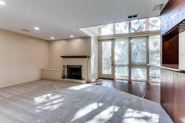 unfurnished living room with carpet, a wealth of natural light, and a brick fireplace